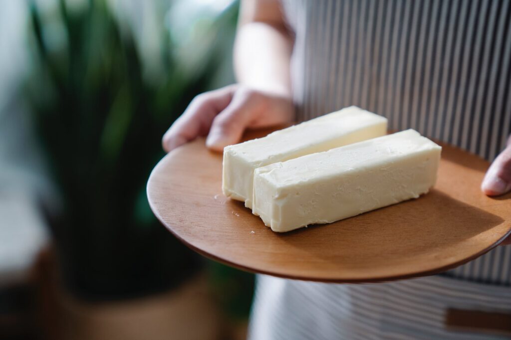 close up shot of a person holding a wooden plate with sliced butters