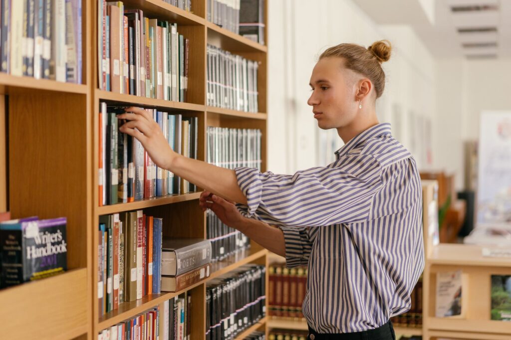 a young man looking at books in a library