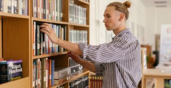 a young man looking at books in a library