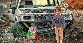 girl with backpack near broken car ruins