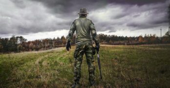 man in camouflage suit holding shotgun